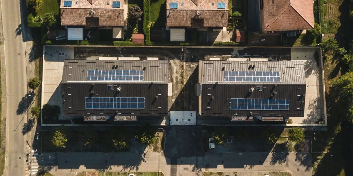 Vista aerea di due edifici residenziali con coperture scure e pannelli fotovoltaici installati sui tetti.